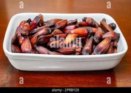 Frutta di pinoli al forno su piatto quadrato bianco su sfondo rustico Foto Stock