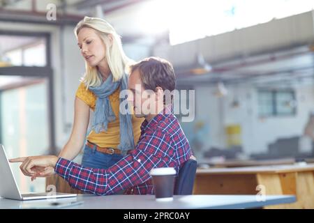 Trovare soluzioni insieme. due designer che lavorano su un notebook in ufficio. Foto Stock