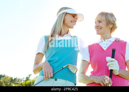 Golf amici con mamma. Due donne attraenti che tengono i randelli di golf ed in piedi con il loro golf cart. Foto Stock