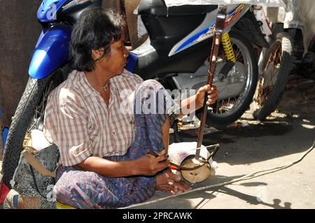 Un anziano uomo tailandese che suona lo strumento a corda ad arco di Saw Duang sulla strada nel centro di Bangkok, Thailandia. Foto Stock