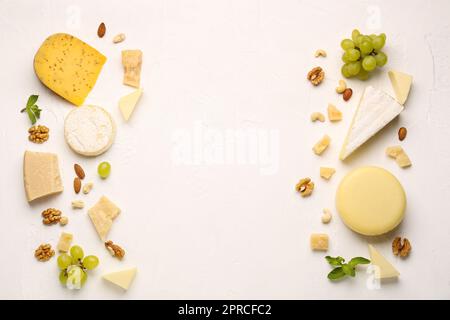 Cornice fatta di diversi tipi di formaggio, uva e noci gustosi su sfondo chiaro Foto Stock