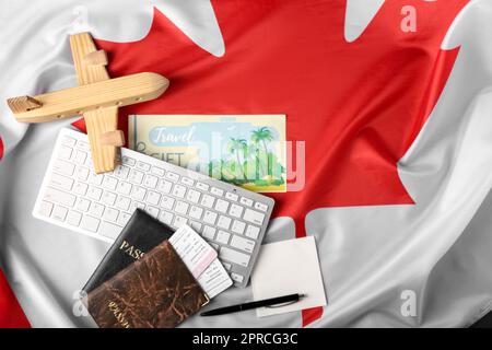 Tastiera per computer con passaporti, biglietti, aeroplano di legno e note appiccicose sulla bandiera canadese Foto Stock