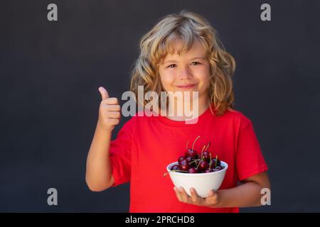 Ciliegia per i bambini. Piastra per bambini con ciliegie su sfondo grigio. Foto Stock