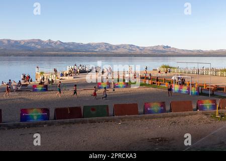 Persone che si riuniscono e giocano a una partita di calcio sul lungofiume di Nahuel Huapi Lake Beach. Giorno di sole nella città di San Carlos De Bariloche, Patagonia Argentina Foto Stock