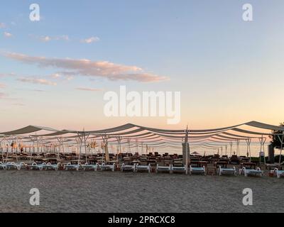 Lettini e ombrelloni sulla spiaggia sul mare in vacanza in una località turistica tropicale orientale caldo paese sud. Foto Stock