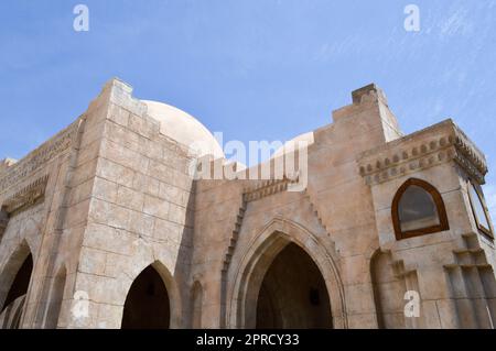 Un muro con una bella texture di una moschea islamica araba fatta di architettura di mattoni bianchi con archi, alte torri, cupole e porte e scolpite Foto Stock