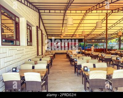 ampio salone con tavoli e sedie. sala da pranzo in hotel per i pasti. turisti a pranzo. tavoli sotto il tetto per proteggere dal sole. Foto Stock