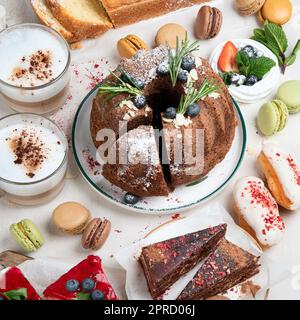 Tavolo da dessert con vari tipi di torte, pezzetti di torte, dolci, biscotti con condimenti di frutta su sfondo bianco. Vista dall'alto. Foto Stock