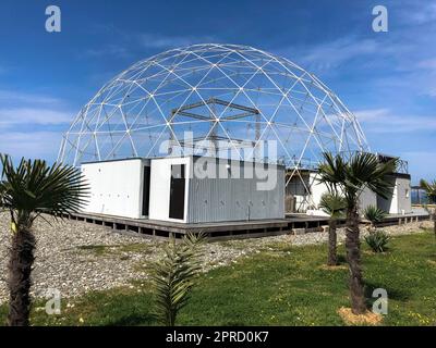 Sferico rotondo astratto costruzione costruzione metallo bianco di triangoli su una spiaggia sabbiosa contro il mare e il cielo blu. Foto Stock