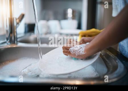 Mani, lavello e piatti di pulizia con una persona in cucina di una casa per lavare un piatto per l'igiene. Acqua, batteri e sapone con un lavaggio per adulti Foto Stock