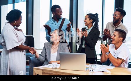 Riteniamo che lei meriti questa promozione: Un gruppo di uomini d'affari che applaude i colleghi in un ufficio. Foto Stock