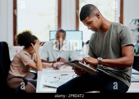 Lo strumento perfetto per un manager moderno. Un giovane uomo d'affari che utilizza un tablet digitale durante una riunione in un ufficio moderno. Foto Stock