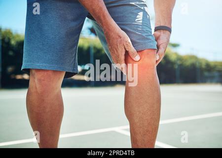 Ive mi ha fatto male. Uno sportivo irriconoscibile che soffre di una lesione al ginocchio mentre giocava a tennis da solo. Foto Stock