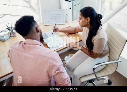 Credo che dobbiamo concentrarci su questo punto: Due giovani uomini d'affari seduti insieme in ufficio e che passano attraverso la documentazione. Foto Stock