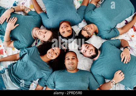 Fare una pausa. Ritratto ad angolo alto di un gruppo diversificato di amici sdraiati in un cerchio durante una classe d'arte. Foto Stock