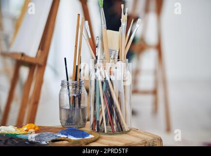 Lasciate che la spazzola vi guidi. Foto di vita di pennelli in vasetti in uno studio d'arte. Foto Stock