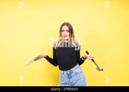 Centro servizi. Riparazione del notebook. Il cacciavite femmina svita i bulloni del computer portatile su sfondo giallo Foto Stock