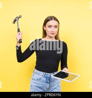 Centro servizi. Riparazione del notebook. Il cacciavite femmina svita i bulloni del computer portatile su sfondo giallo Foto Stock