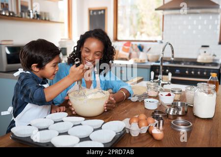 Questo piccolo panettiere migliora con ogni cottura. Una donna che cuoce a casa con il suo figlio giovane. Foto Stock