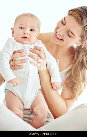 Ritratta una madre felice che si unisce al suo bambino a casa, godendoti momenti divertenti di genitorialità. Giovane donna affettuosa e amorevole con il suo neonato, giocando e trascorrendo del tempo insieme Foto Stock