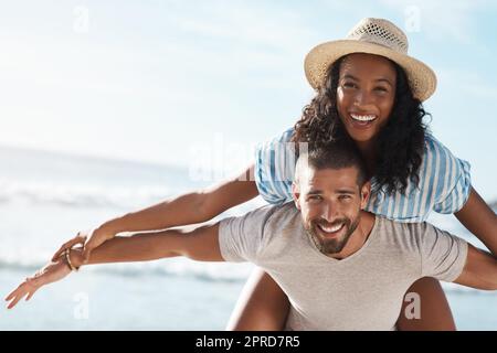 Volavano in un'estate piena di divertimento. Ritratto di un giovane piggybacking la sua ragazza alla spiaggia. Foto Stock