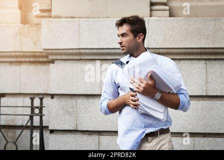 Devo continuare a muovermelo: Un giovane che ha sottolineato la necessità di tenere un mucchio di documenti cartacei mentre camminava al lavoro la mattina. Foto Stock