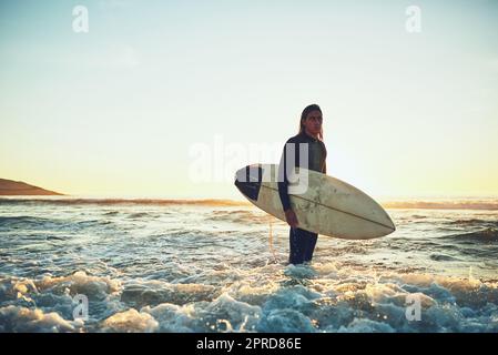 Mi piace stare fuori nel grande mare blu, un giovane che porta una tavola da surf in spiaggia. Foto Stock