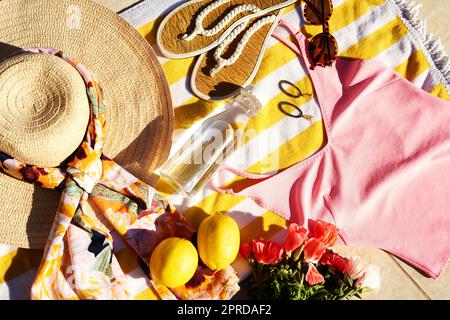 Estate accogliente con colori luminosi. Scatto ad angolo alto di abbigliamento estivo ordinato e posato su un telo da spiaggia durante il giorno. Foto Stock