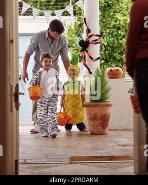 Halloween è sempre un vero piacere. Sparo a tutta lunghezza di un padre e dei suoi adorabili figli giovani trick o trattando insieme su Halloween. Foto Stock