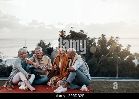 Tempo per rilassarsi con un po' di vino a portata di mano. Shot completo di una famiglia affettuosa che ha vino insieme mentre festeggia un nuovo anno all'aperto. Foto Stock