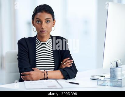 Shes serio e determinato per riuscire. Ritratto di una giovane donna d'affari attraente che si posa alla sua scrivania d'ufficio al lavoro. Foto Stock