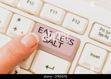 Testo calligrafico Eat Less Salt. Idea di business ridurre la quantità di sodio nella vostra dieta mangiare sano messaggi importanti scritti su due Note sulla scrivania con tastiera. Foto Stock