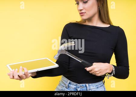 Centro servizi. Riparazione del notebook. Il cacciavite femmina svita i bulloni del computer portatile su sfondo giallo Foto Stock