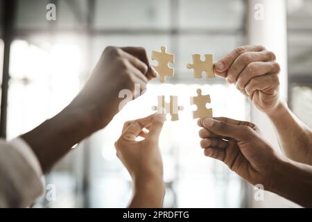 Team diversificato che risolve un problema insieme grazie al lavoro di squadra, al supporto e all'assistenza reciproca in ufficio. Gruppo di uomini d'affari che assemblano un puzzle e collaborano in unità Foto Stock