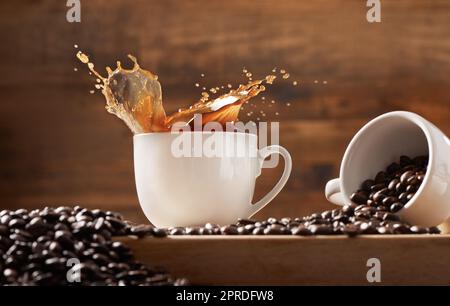 Mi piace il caffè riempito fino al bordo: Due tazze su sfondo di legno pieno di caffè e chicchi di caffè. Foto Stock