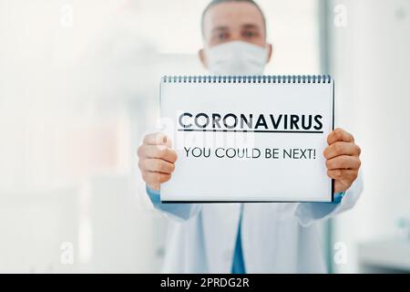 Questo virus non discrimina. Uno scienziato che ha un segno con CORONAVIRUS-SI POTREBBE ESSERE PROSSIMO su di esso in un laboratorio. Foto Stock