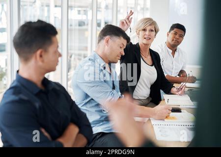 Una domanda che suscita una conferenza di affari. Una donna d'affari matura che alza la mano per fare le domande durante una riunione. Foto Stock
