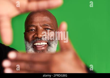 Tutti vogliono vedere quel volto sorridente. Studio girato di un uomo anziano formando una cornice per le dita davanti al suo volto. Foto Stock