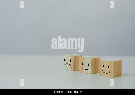 Servizio clienti e soddisfazione concetto felice Smiley faccia Icon.Business feedback positivo rating molto impressionato cubo di legno sulla tavola. Foto Stock