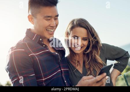 Tutti commentano la nostra immagine. Foto in primo piano di una giovane donna attraente che fa facce divertenti mentre il suo fidanzato la fotografa all'aperto. Foto Stock