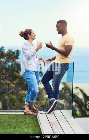 Godendo un certo tempo molto necessario a noi stessi. Foto a tutta lunghezza di una giovane coppia gustando un drink insieme mentre si rilassa all'aperto in vacanza. Foto Stock