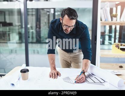 Gli investitori saranno in tutto questo progetto. Un architetto maschio maturo che lavora su un disegno nel suo ufficio. Foto Stock