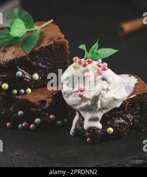 Pezzi cotti di torta brownie al cioccolato su un tavolo nero, sulla parte superiore di una paletta di gelato Foto Stock