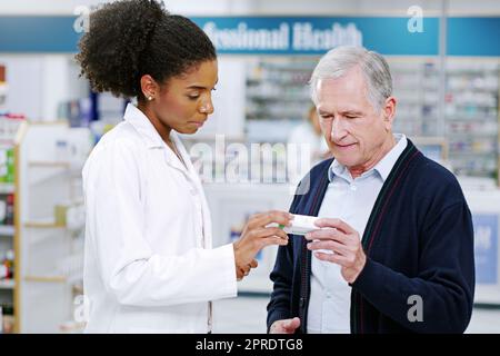 La qualità del servizio è più preziosa della vendita: Un giovane farmacista raccomanda un prodotto sanitario a un anziano in farmacia. Foto Stock