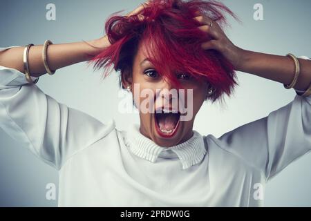 Ha il fuoco nella sua anima. Studio shot di una giovane donna attraente urlare su uno sfondo grigio. Foto Stock