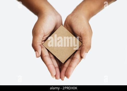 Primo piano delle mani di una persona che mostra un messaggio, pubblicizza un prodotto o tiene in mano una carta vuota o una carta di cartone su sfondo bianco. Vista dall'alto della donna che promuove un oggetto o un segno Foto Stock