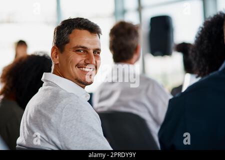 Im imparare così tanto. Ritratto ritagliato di un bel giovane uomo d'affari seduto nella sala conferenze durante un seminario. Foto Stock