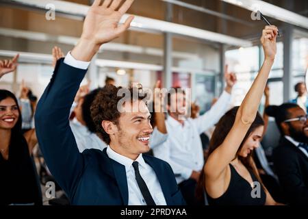 Hanno tante domande: Un gruppo di giovani uomini d'affari seduti con le mani alzate durante un seminario nella sala conferenze. Foto Stock