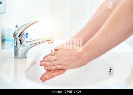 Ogni goccia conta. Primo piano di una donna irriconoscibile che si lava le mani nel lavandino del bagno a casa. Foto Stock