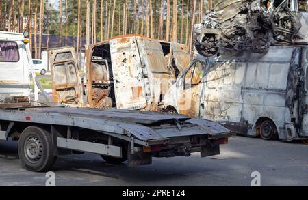 Molte vecchie auto pronte per il riciclaggio. Rimozione della vettura tramite rimorchio. L'auto si sta preparando per essere caricata su un rimorchio. Vecchie auto distrutte in una discarica aspettano di essere distrutte in un parco di riciclaggio. Foto Stock